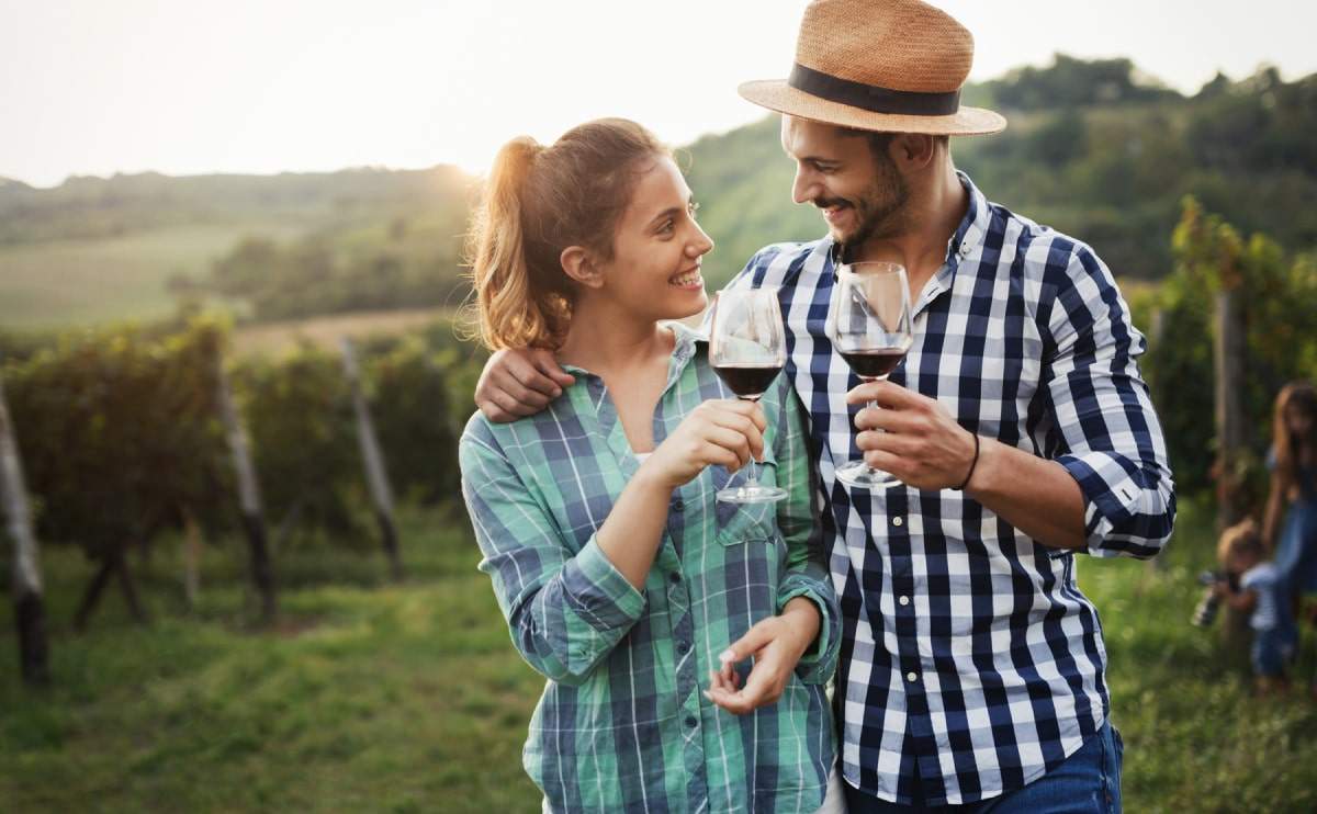 Kontakt - Paar genießt Rotwein im Weinberg bei Sonnenuntergang – La Bona Vida